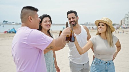 Foto de Grupo de personas brindando con una botella de cerveza en la playa - Imagen libre de derechos