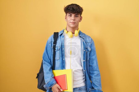 Photo for Hispanic teenager wearing student backpack and holding books looking sleepy and tired, exhausted for fatigue and hangover, lazy eyes in the morning. - Royalty Free Image