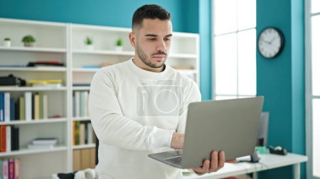 Téléchargez les photos : Jeune homme hispanique étudiant utilisant un ordinateur portable à l'université de la bibliothèque - en image libre de droit