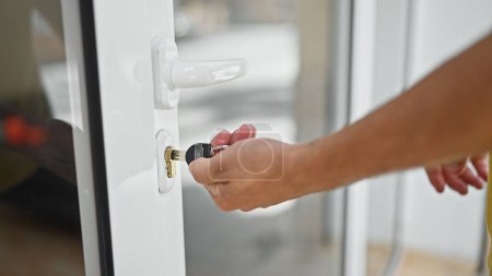 Téléchargez les photos : Jeune homme hispanique fermer la porte en utilisant la clé à la maison - en image libre de droit