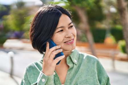 Téléchargez les photos : Young chinese woman smiling confident talking on the smartphone at park - en image libre de droit