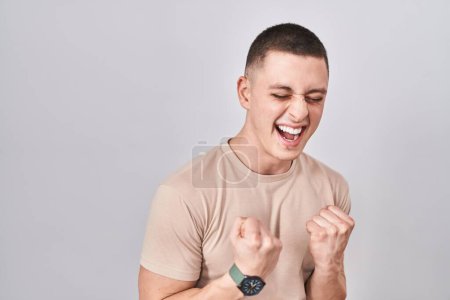 Photo for Young man standing over isolated background very happy and excited doing winner gesture with arms raised, smiling and screaming for success. celebration concept. - Royalty Free Image