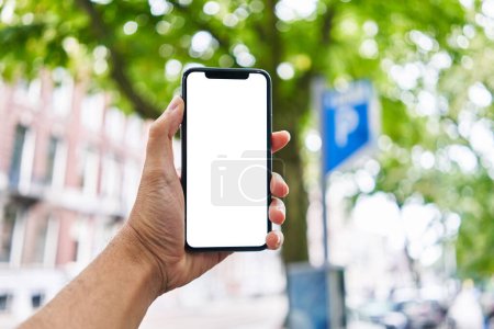 Téléchargez les photos : Homme tenant smartphone montrant écran blanc au parking - en image libre de droit