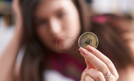 Photo for Young caucasian woman holding uniswap coin at home - Royalty Free Image