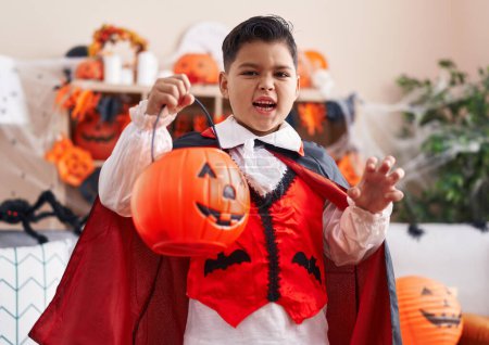 Foto de Adorable niño hispano con disfraz de halloween haciendo un gesto aterrador en casa - Imagen libre de derechos
