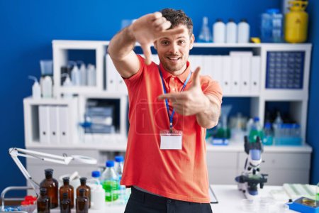 Photo for Young hispanic man working at scientist laboratory smiling making frame with hands and fingers with happy face. creativity and photography concept. - Royalty Free Image