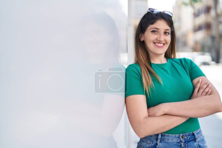 Téléchargez les photos : Jeune femme hispanique souriante confiante debout avec les bras croisés geste à la rue - en image libre de droit