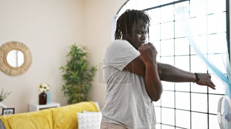 Foto de Africano americano hombre estirando brazos en casa - Imagen libre de derechos