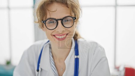 Téléchargez les photos : Jeune femme médecin portant des lunettes souriant à la clinique - en image libre de droit