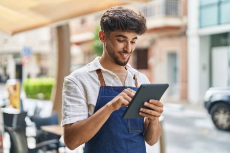 Téléchargez les photos : Young arab man waiter using touchpad working at restaurant - en image libre de droit