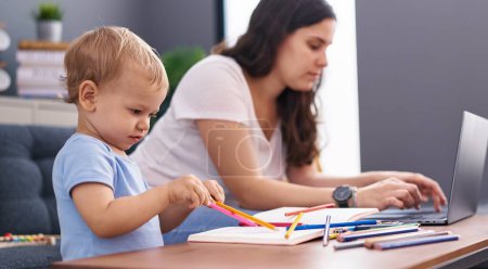 Photo for Mother and son drawing on notebook using laptop at home - Royalty Free Image