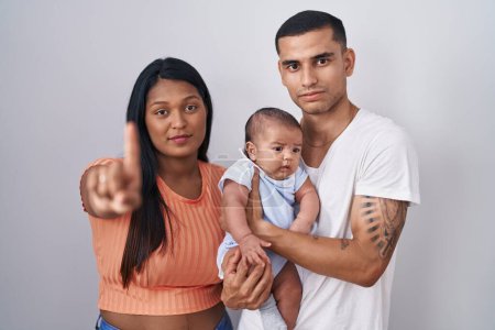 Photo for Young hispanic couple with baby standing together over isolated background pointing with finger up and angry expression, showing no gesture - Royalty Free Image