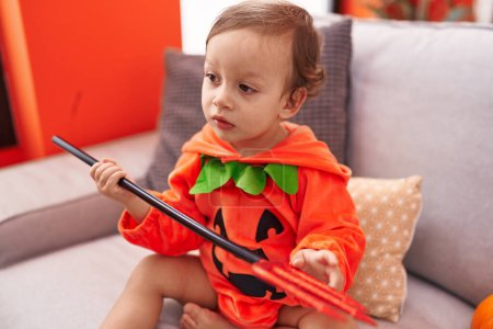 Photo for Adorable hispanic boy wearing pumpkin costume holding trident at home - Royalty Free Image