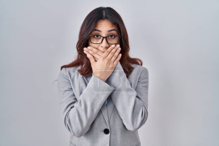 Foto de La joven empresaria hispana que llevaba gafas sorprendió cubriendo la boca con las manos por error. concepto secreto. - Imagen libre de derechos