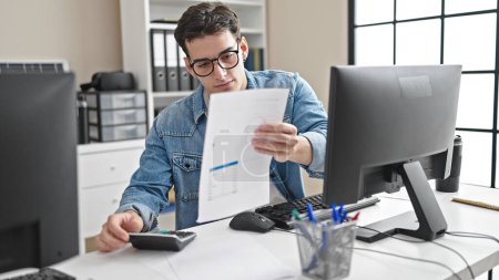 Foto de Joven trabajador de negocios hispano usando documento de lectura de computadora en la oficina - Imagen libre de derechos