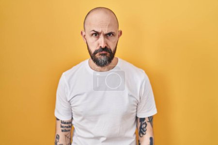 Photo for Young hispanic man with tattoos standing over yellow background depressed and worry for distress, crying angry and afraid. sad expression. - Royalty Free Image