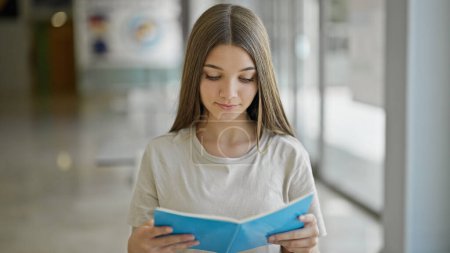 Téléchargez les photos : Jeune belle fille étudiant livre de lecture à la bibliothèque - en image libre de droit