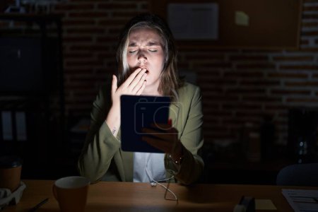 Photo for Blonde caucasian woman working at the office at night bored yawning tired covering mouth with hand. restless and sleepiness. - Royalty Free Image