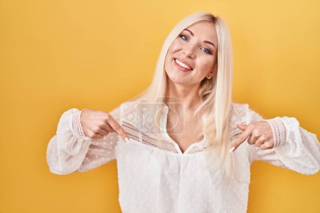 Photo for Caucasian woman standing over yellow background looking confident with smile on face, pointing oneself with fingers proud and happy. - Royalty Free Image