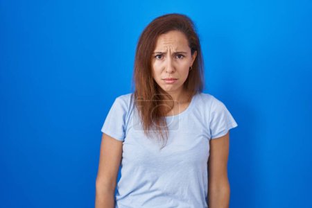 Photo for Brunette woman standing over blue background depressed and worry for distress, crying angry and afraid. sad expression. - Royalty Free Image