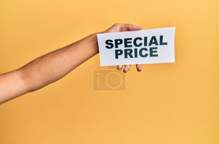 Photo for Hand of caucasian man holding paper with special price message over isolated yellow background - Royalty Free Image