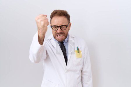 Photo for Middle age doctor man with beard wearing white coat angry and mad raising fist frustrated and furious while shouting with anger. rage and aggressive concept. - Royalty Free Image