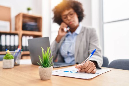 Téléchargez les photos : African american woman business worker talking on smartphone writing on document at office - en image libre de droit