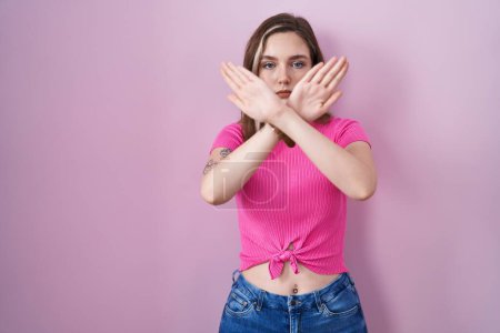 Photo for Blonde caucasian woman standing over pink background rejection expression crossing arms and palms doing negative sign, angry face - Royalty Free Image