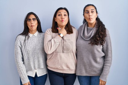 Photo for Mother and two daughters standing over blue background making fish face with lips, crazy and comical gesture. funny expression. - Royalty Free Image