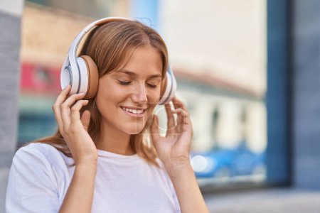 Foto de Young blonde girl smiling confident listening to music at street - Imagen libre de derechos