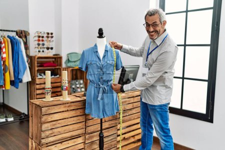 Photo for Middle age grey-haired man shop assistant measuring dress at clothing store - Royalty Free Image