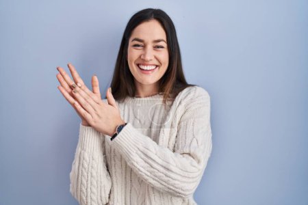 Téléchargez les photos : Jeune femme brune debout sur fond bleu applaudissant et applaudissant heureux et joyeux, souriant mains fiers ensemble - en image libre de droit