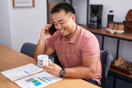 Téléchargez les photos : Jeune homme d'affaires chinois parlant sur smartphone boire du café au bureau - en image libre de droit