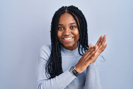 Téléchargez les photos : Femme afro-américaine debout sur fond bleu applaudissements et applaudissements heureux et joyeux, souriant mains fières ensemble - en image libre de droit