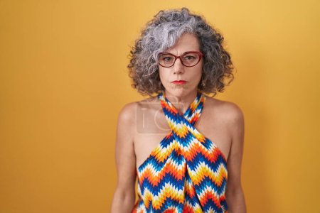 Photo for Middle age woman with grey hair standing over yellow background skeptic and nervous, frowning upset because of problem. negative person. - Royalty Free Image