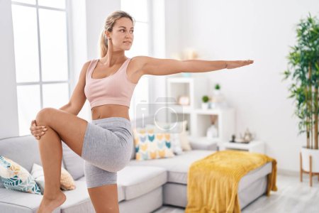 Téléchargez les photos : Jeune femme blonde souriante confiante, entraînement yoga exercice à la maison - en image libre de droit