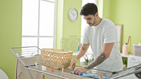 Foto de Joven hispano colgando ropa en tendedero en la lavandería - Imagen libre de derechos