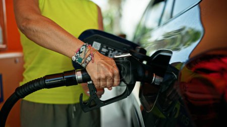 Photo for Middle age hispanic woman putting gas in the car at gas station - Royalty Free Image