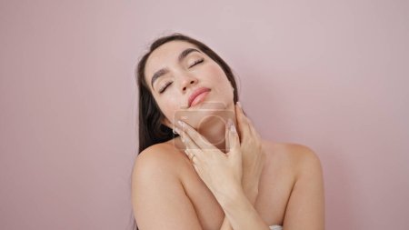 Téléchargez les photos : Jeune belle femme hispanique massant le cou sur fond rose isolé - en image libre de droit