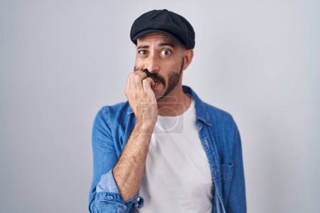 Foto de Hombre hispano con barba de pie sobre un fondo aislado mirando estresado y nervioso con las manos en la boca mordiendo uñas. problema de ansiedad. - Imagen libre de derechos