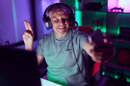 Photo for Middle age grey-haired man streamer make selfie by smartphone at gaming room - Royalty Free Image