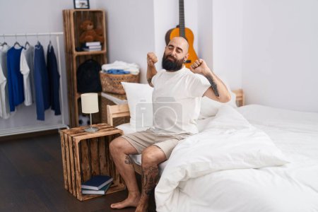 Photo for Young bald man waking up stretching arms at bedroom - Royalty Free Image