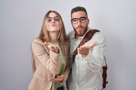 Photo for Young couple standing over white background looking at the camera blowing a kiss with hand on air being lovely and sexy. love expression. - Royalty Free Image