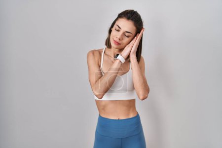 Photo for Hispanic woman wearing sportswear over isolated background sleeping tired dreaming and posing with hands together while smiling with closed eyes. - Royalty Free Image