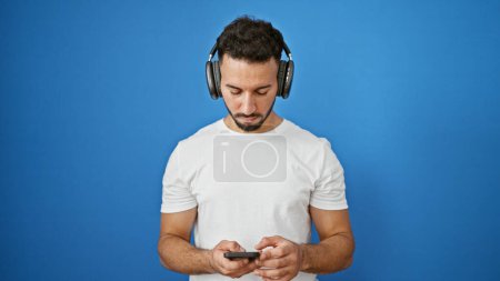 Photo for Young arab man listening to music over isolated blue background - Royalty Free Image