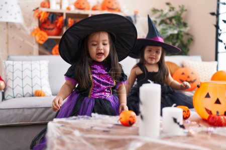 Téléchargez les photos : Adorable jumelles ayant fête d'Halloween souriant confiant à la maison - en image libre de droit