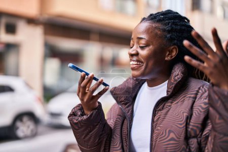 Foto de Mujer afroamericana sonriendo confiada hablando en el teléfono inteligente en la calle - Imagen libre de derechos