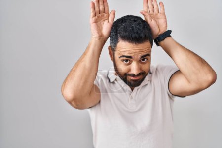 Photo for Young hispanic man with beard wearing casual clothes over white background doing bunny ears gesture with hands palms looking cynical and skeptical. easter rabbit concept. - Royalty Free Image