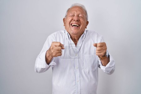 Téléchargez les photos : Homme âgé avec les cheveux gris debout sur fond isolé excité pour le succès avec les bras levés et les yeux fermés célébrant la victoire en souriant. concept gagnant. - en image libre de droit