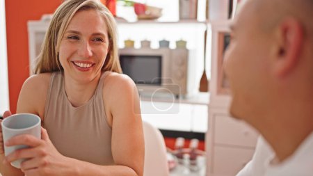 Photo for Man and woman couple holding cup of coffee speaking laughing a lot at dinning room - Royalty Free Image